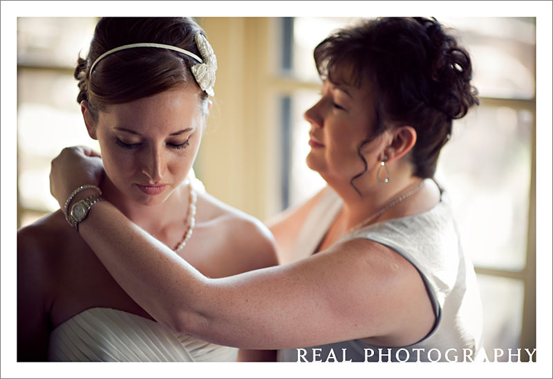 mom helps bride put on necklace